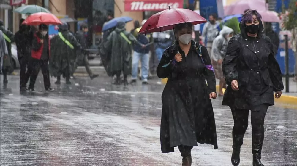 Personas se protegen de la lluvia en una céntrica calle de la ciudad. CRÉDITO: ARCHIVO